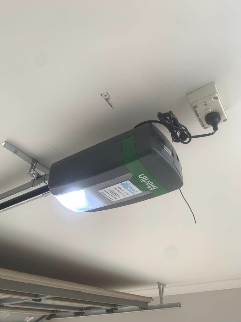 Close-up of a Merlin Garage Door Opener installed in an Australian garage, showcasing its sleek design and modern features like the myQ smartphone control system.

